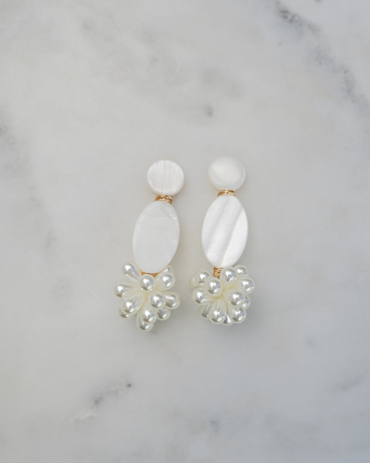 mother of pearl statement earrings on a white marble background