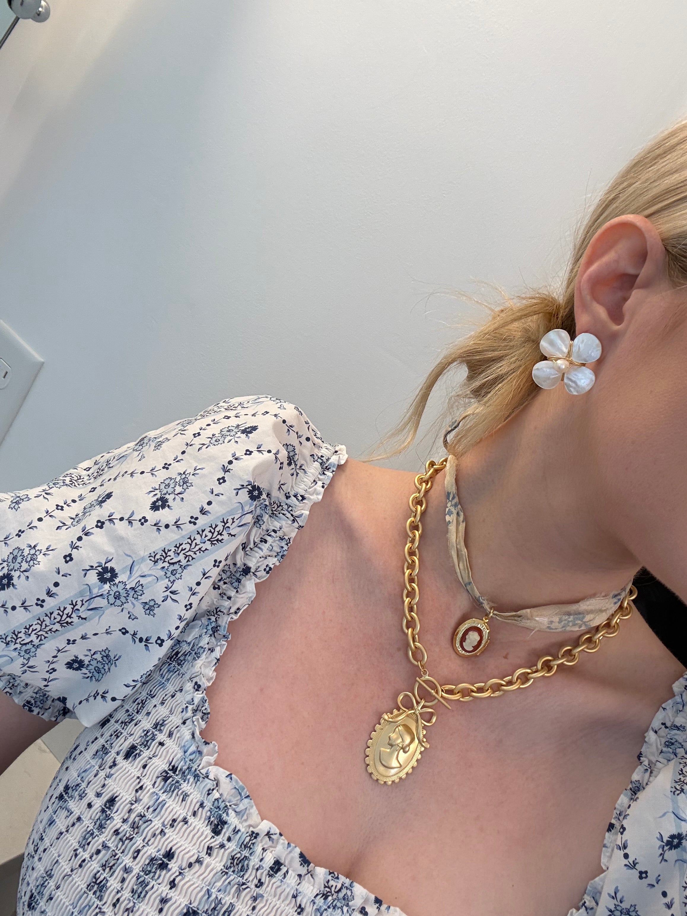 Layered necklaces on a woman in a floral dress