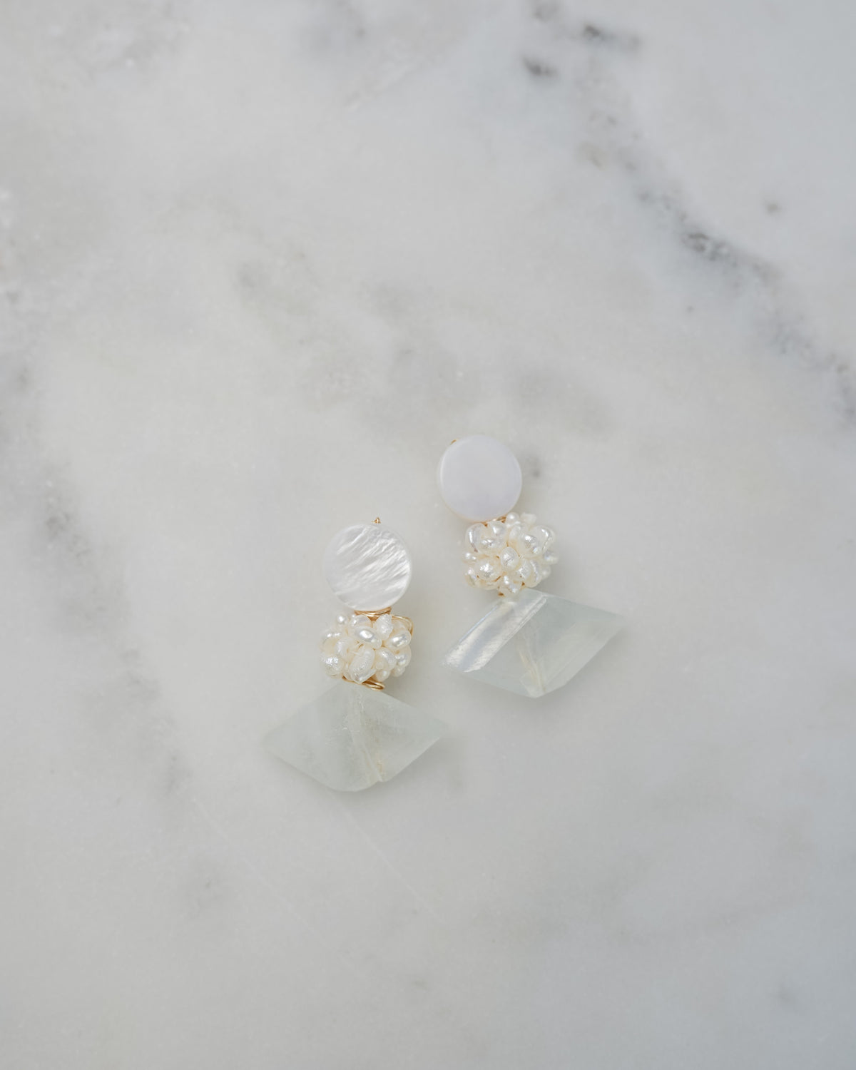 mother of pearl and aquamarine statement earrings on a white marble background