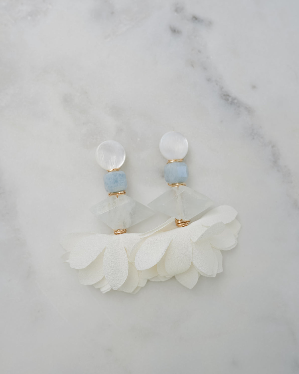 mother of pearl, aquamarine and chiffon petal statement earrings on a white marble background