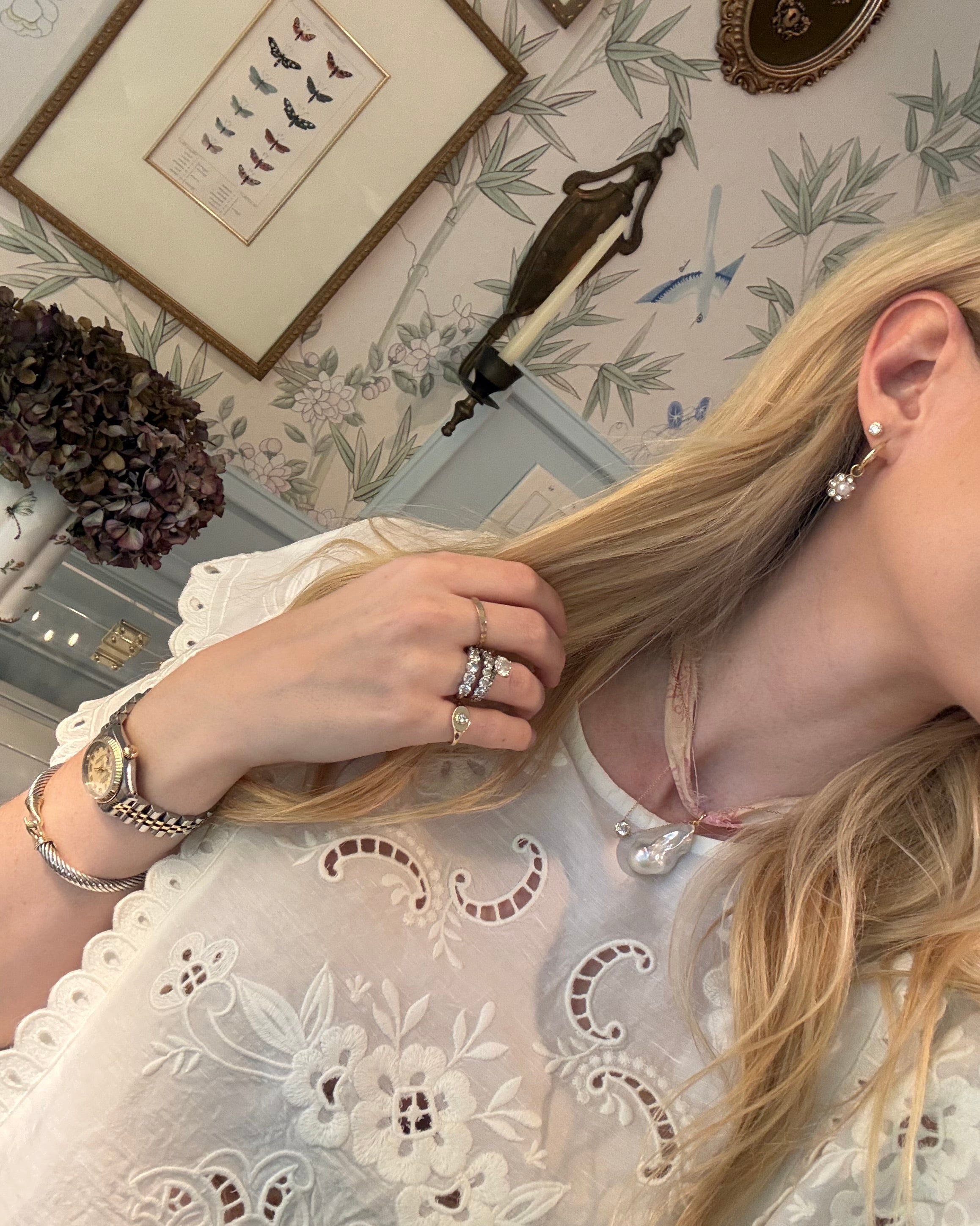 Person with blonde hair in a white lace blouse wearing a single wrap ribbon necklace with a pearl pendant