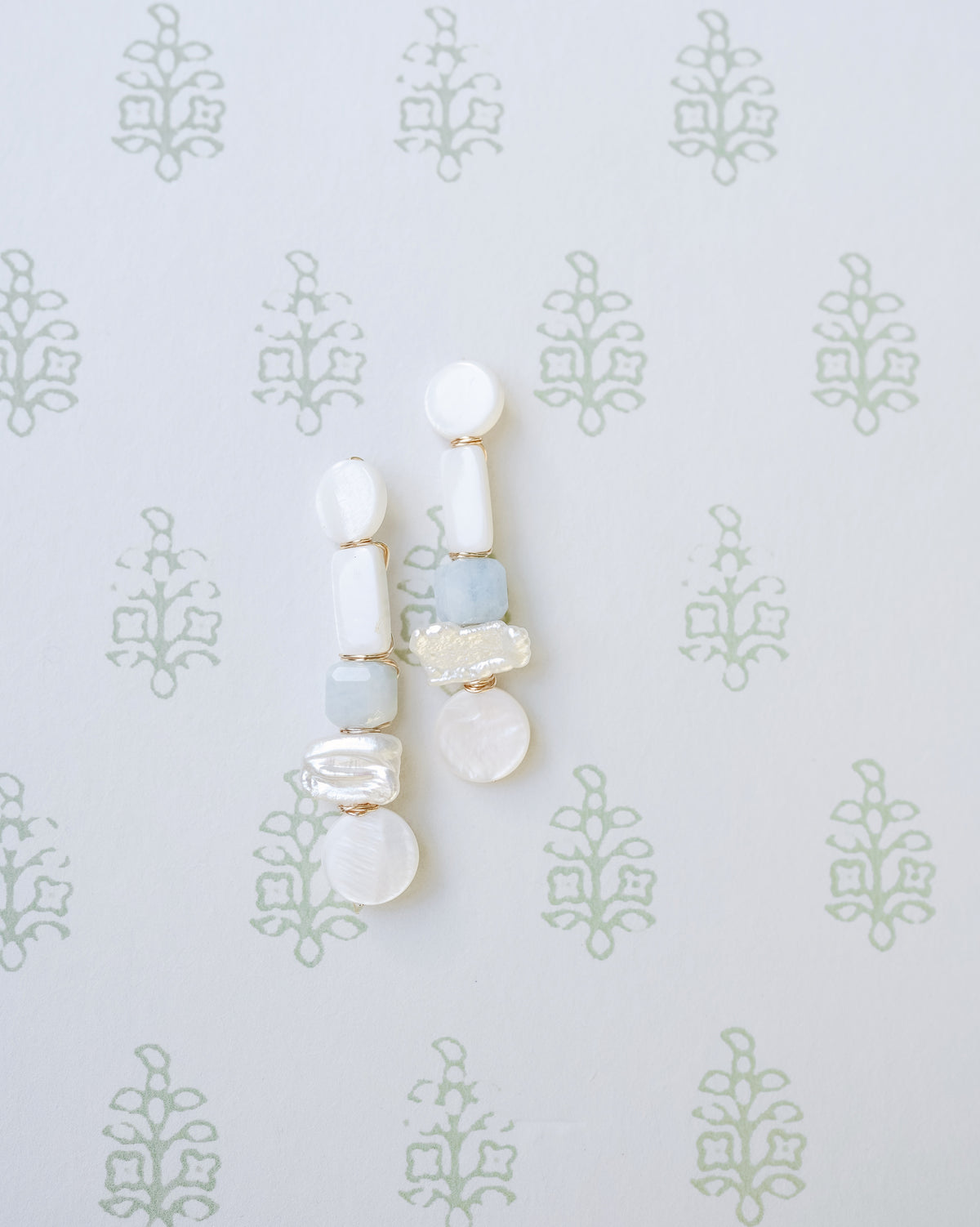 mother of pearl and aquamarine statement earrings on a whiteand green floral background
