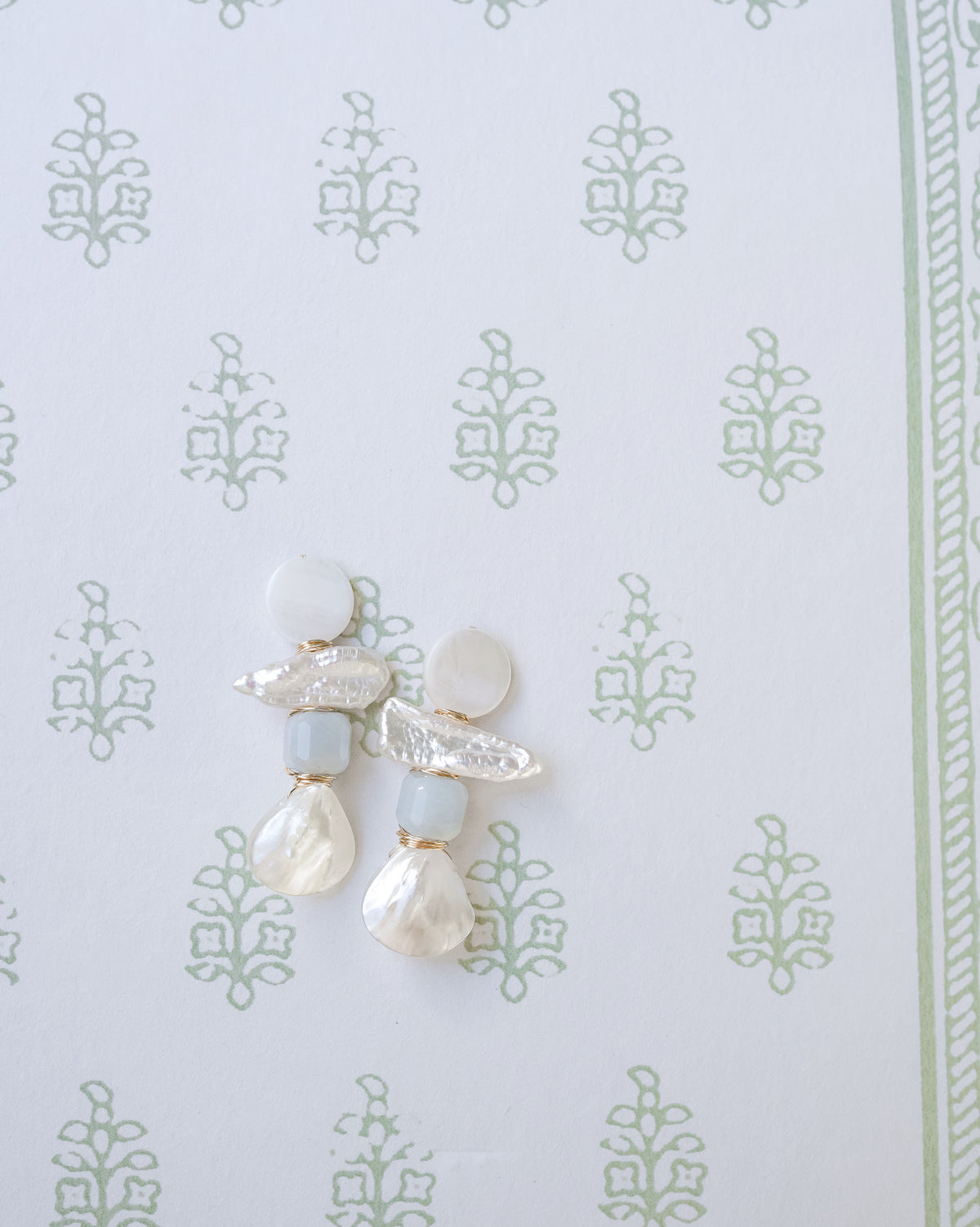 mother of pearl and aquamarine statement earrings on a white and green floral background