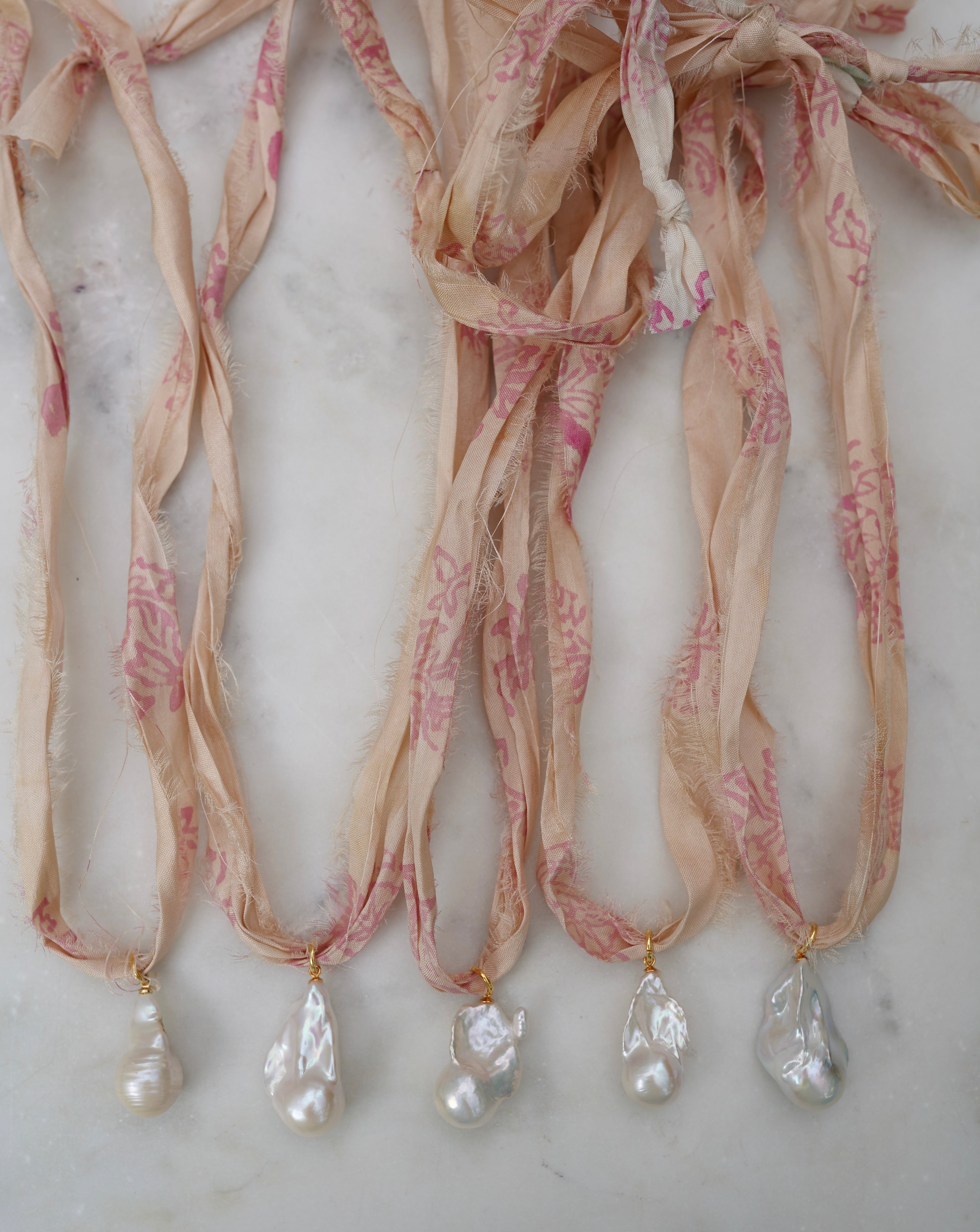 Decorative ribbon necklaces with pearls on a marble surface