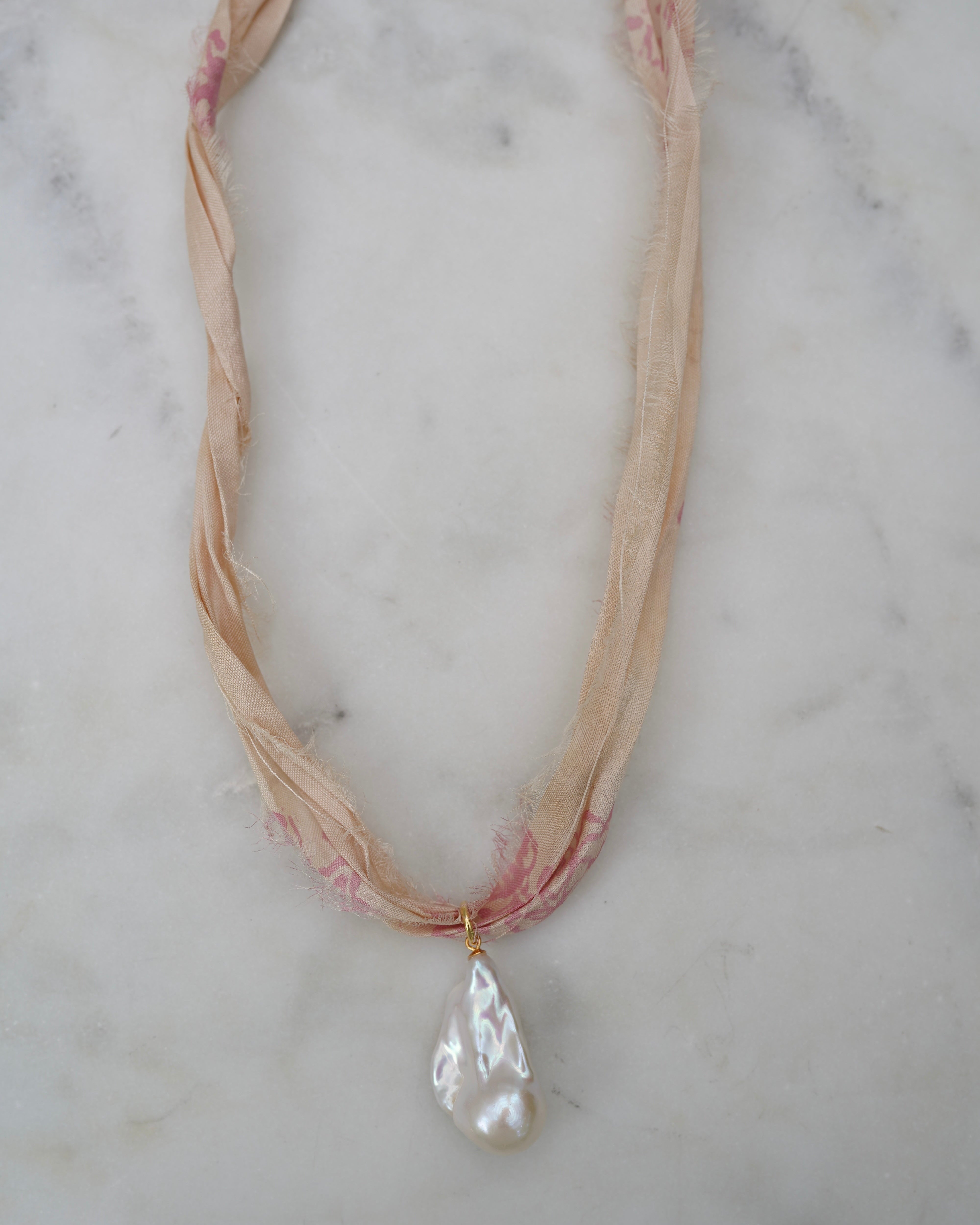Necklace with a large pearl pendant on a marble surface