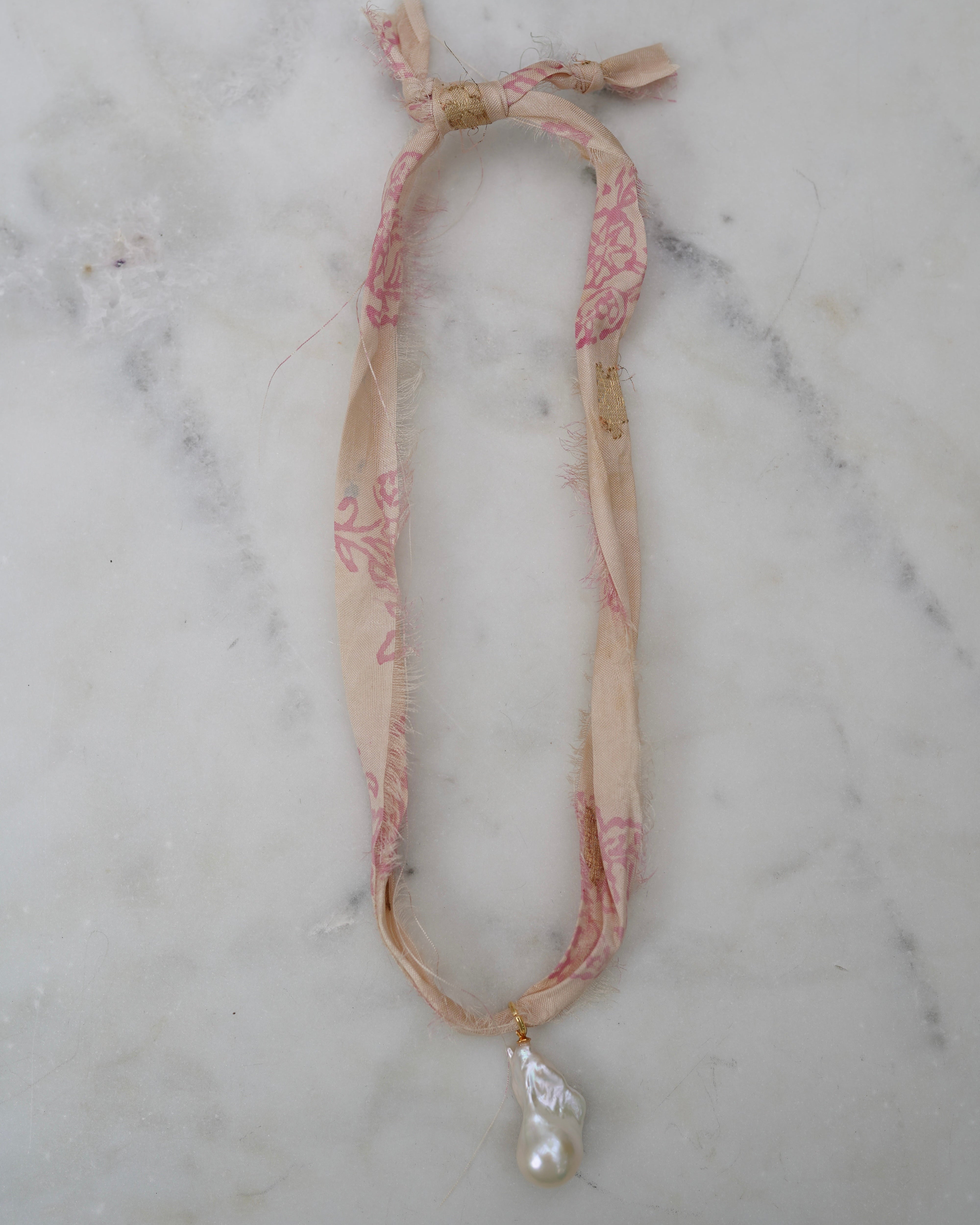 Necklace with a pearl pendant on a marble surface