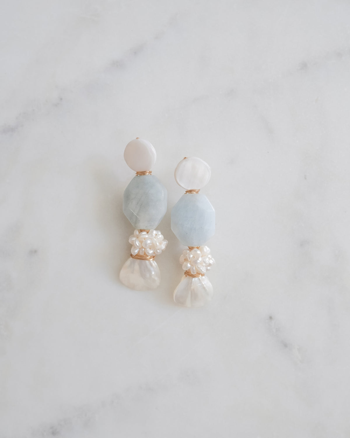 Mother of Pearl and aquamarine statement earrings on a white marble background