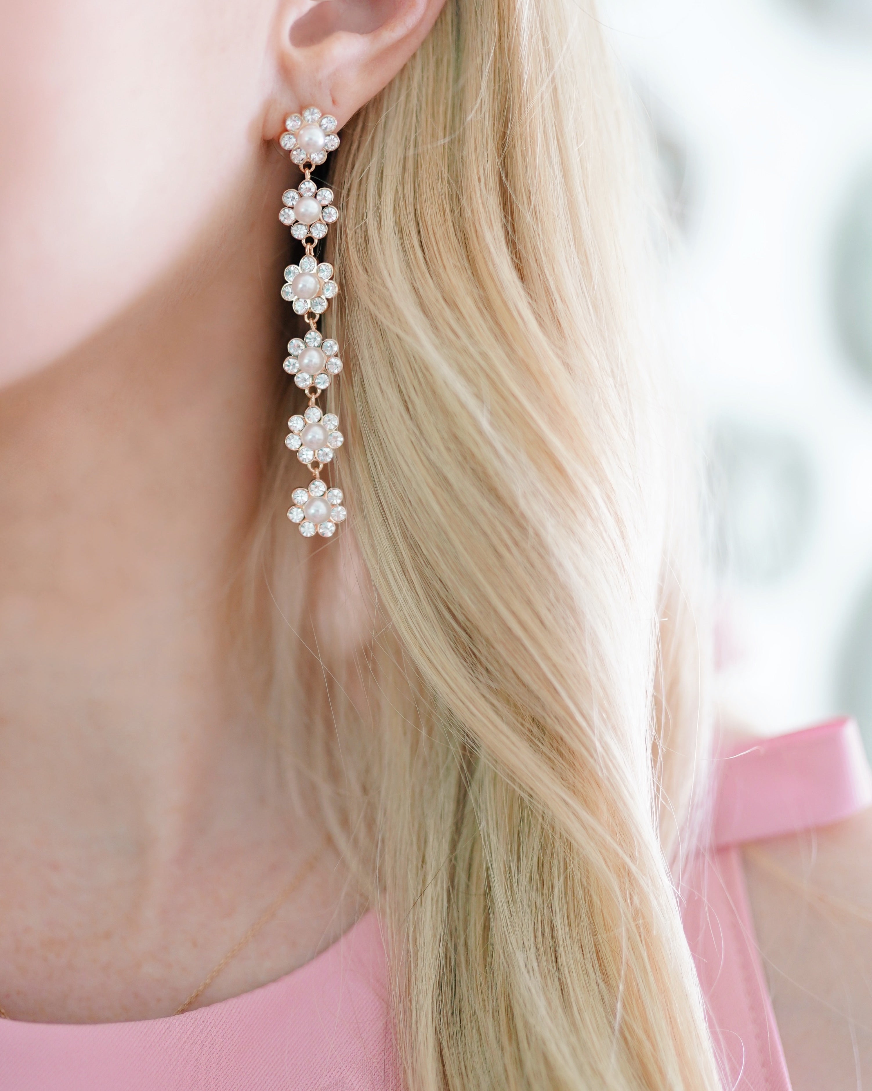 Blonde woman in pink dress wearing sj bailey co crystal and floral earrings