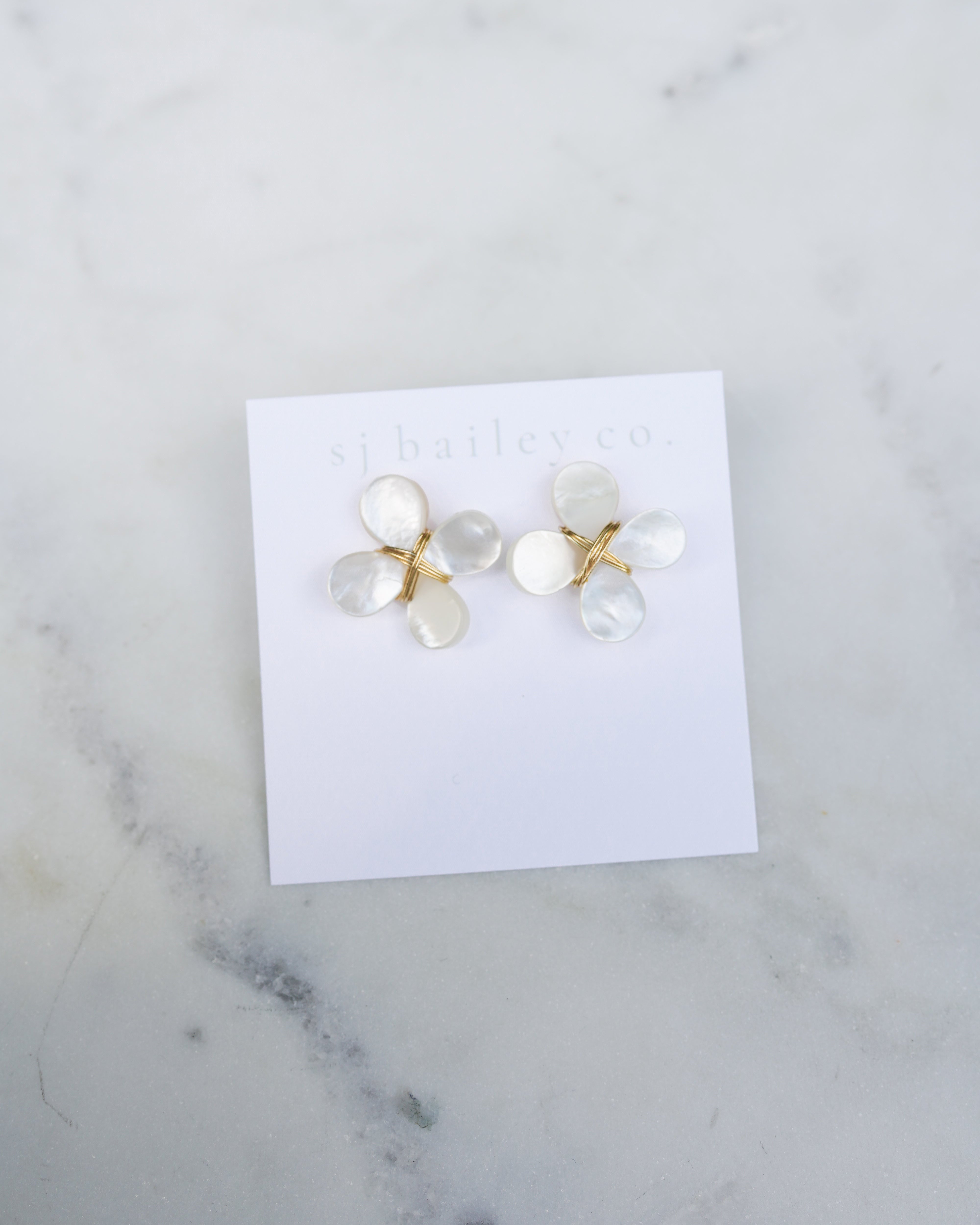Pair of earrings on a white card with a marble background