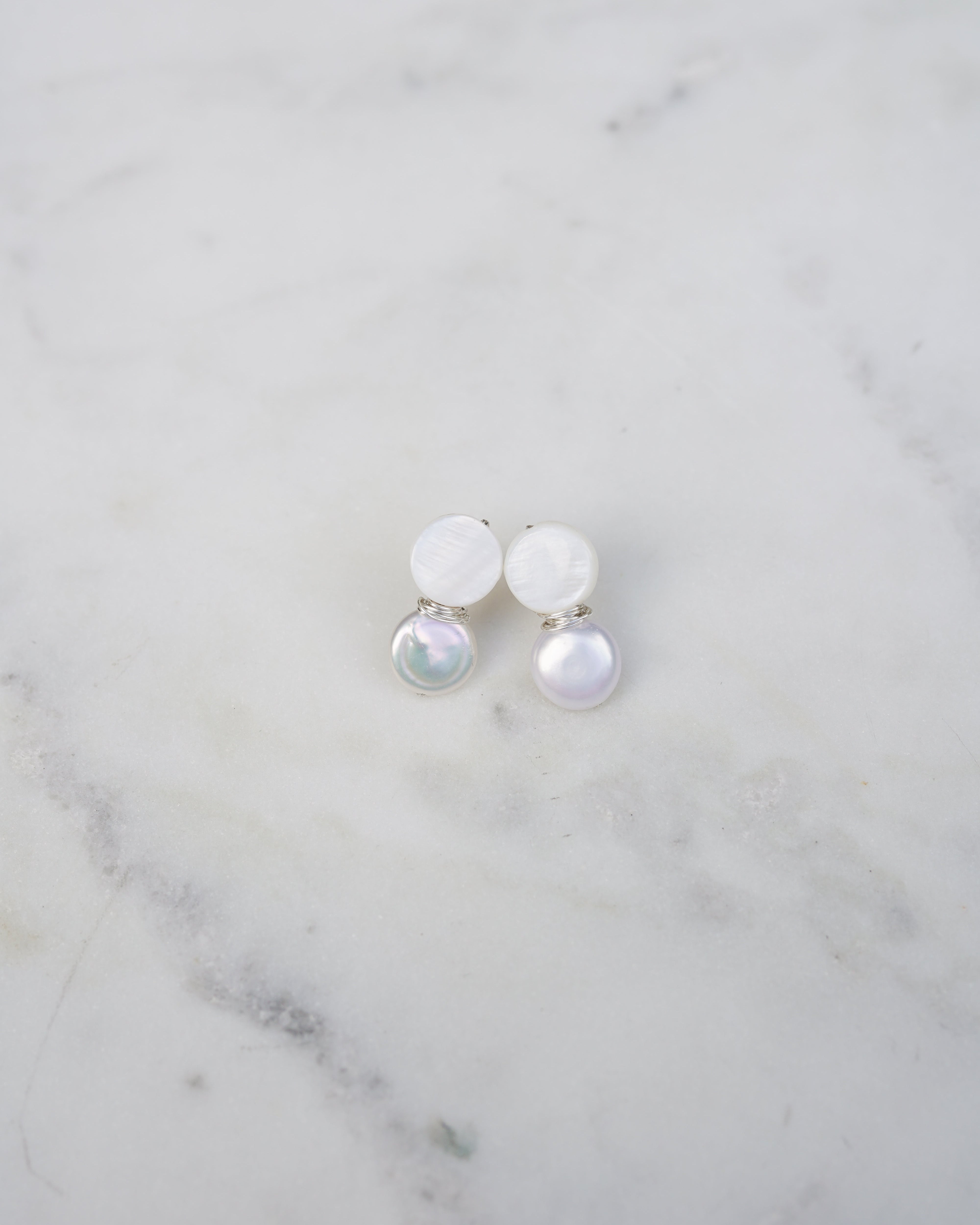 Pair of pearl earrings on a marble surface