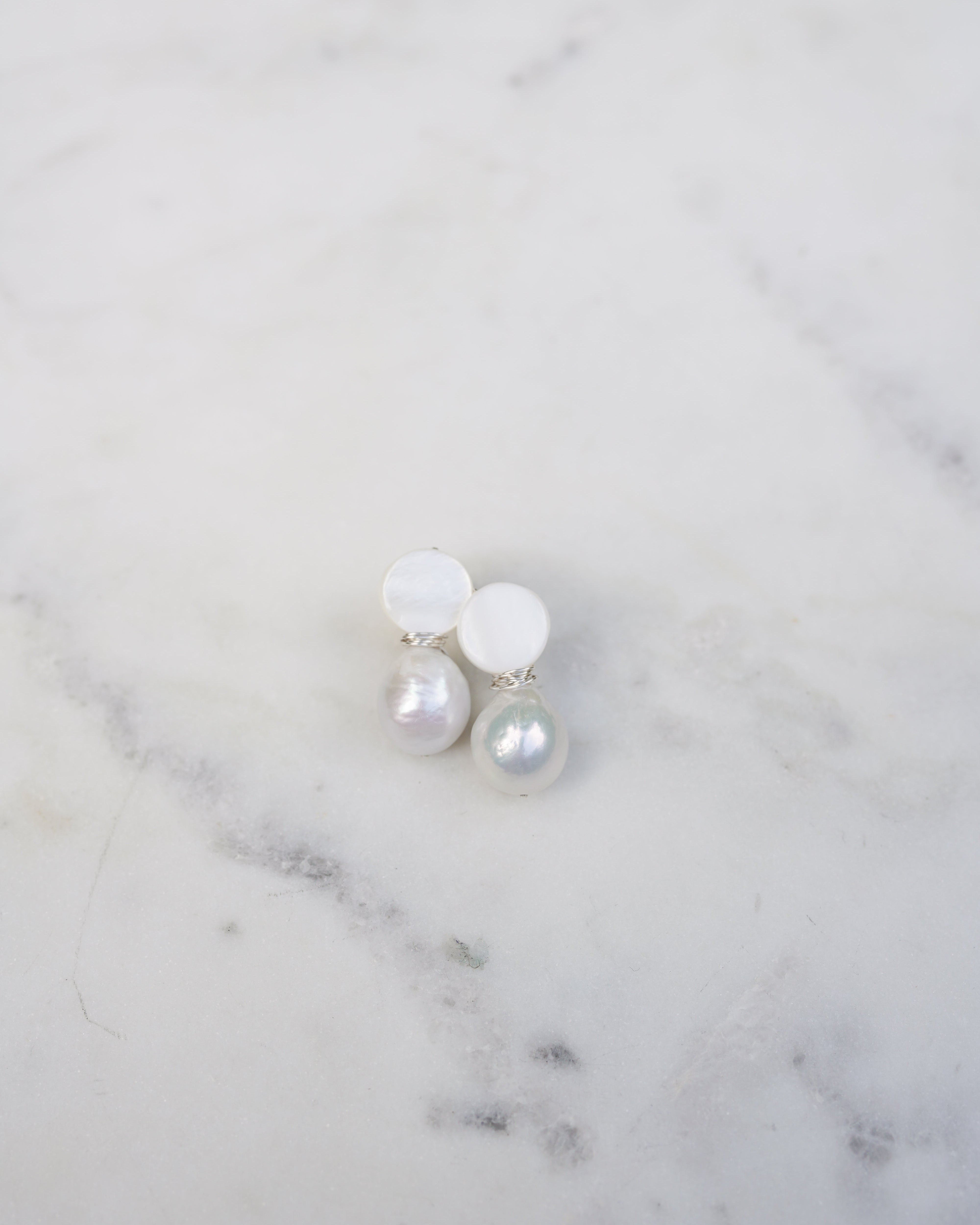Pearl earrings on a marble surface