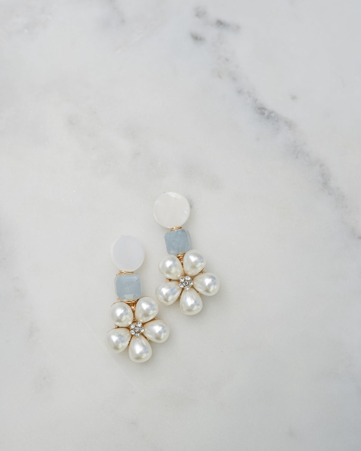mother of pearl and aquamarine statement earrings on a white marble background