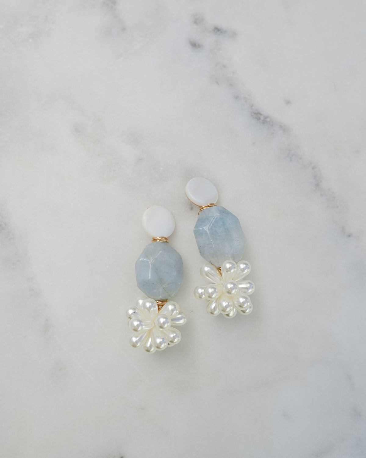 mother of pearl and aquamarine statement earrings on a white marble background