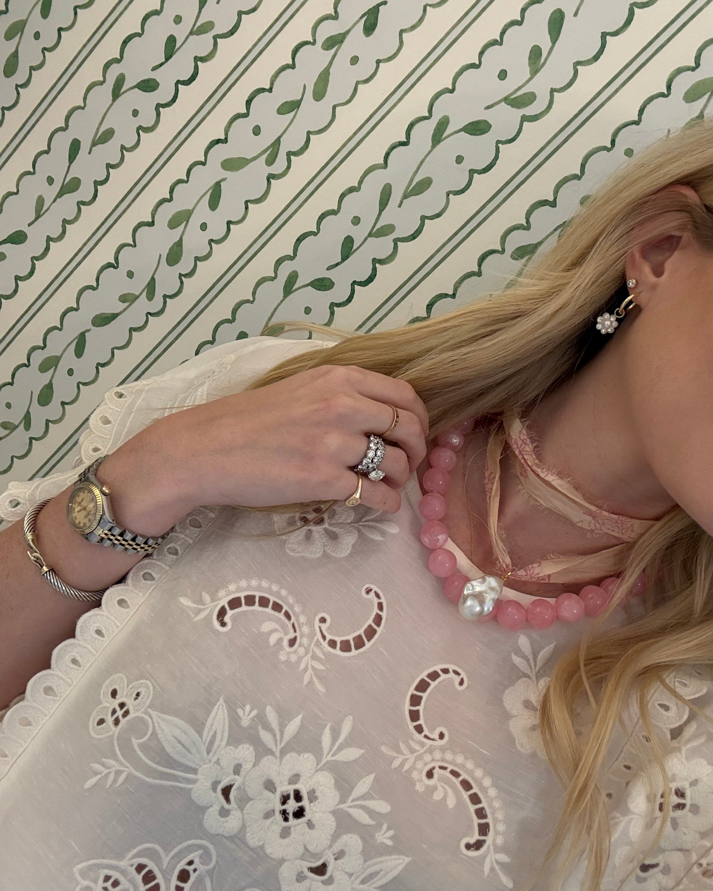 Person with blonde hair in a white lace blouse wearing a double wrap ribbon necklace with a pearl pendant 