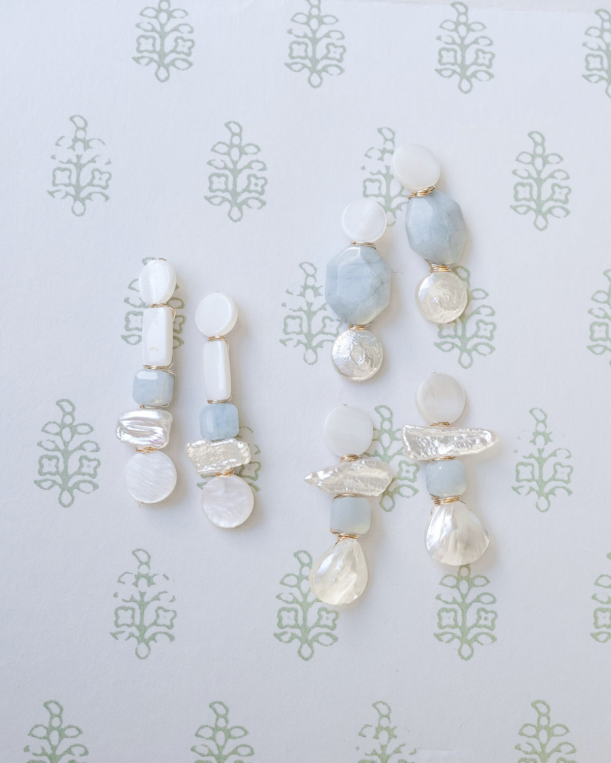 mother of pearl and aquamarine statement earrings on a white and green floral background
