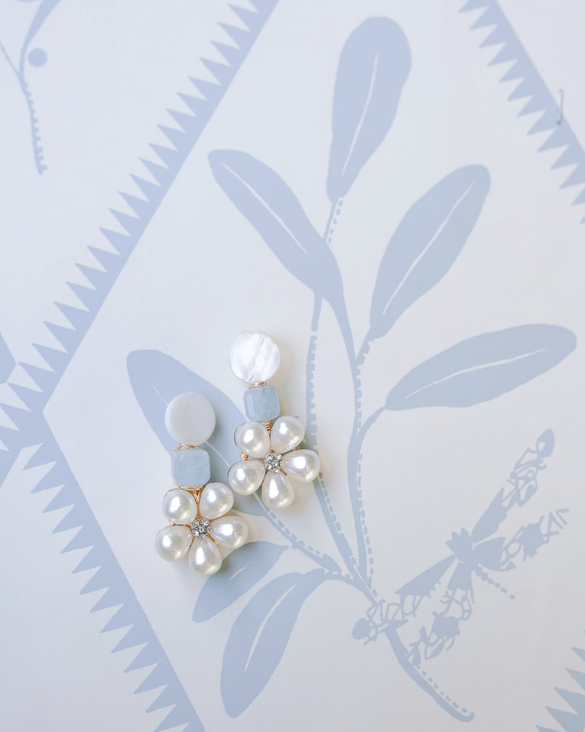 mother of pearl and aquamarine statement earrings on a white and blue floral background