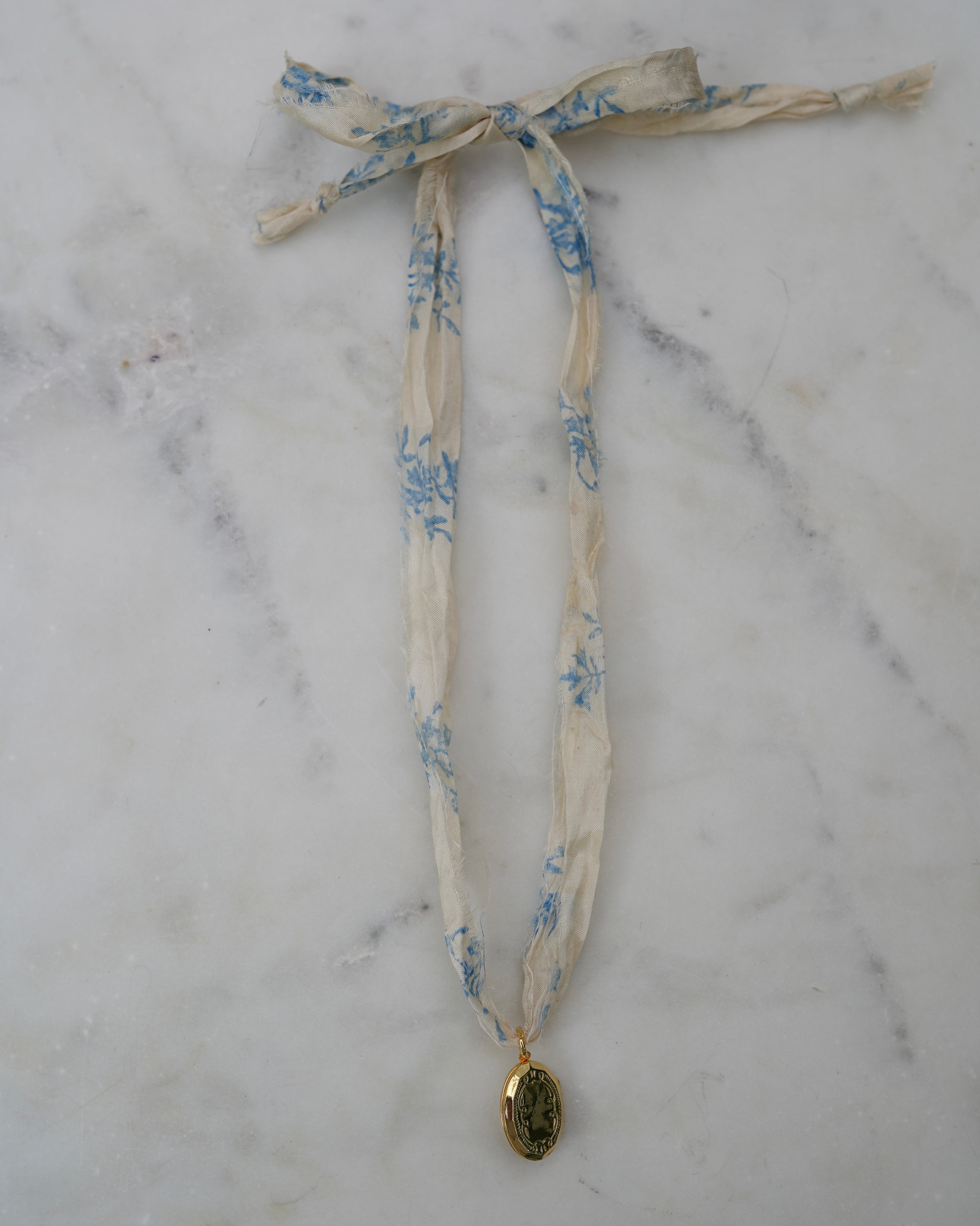 Necklace with floral ribbon and pendant on a marble surface