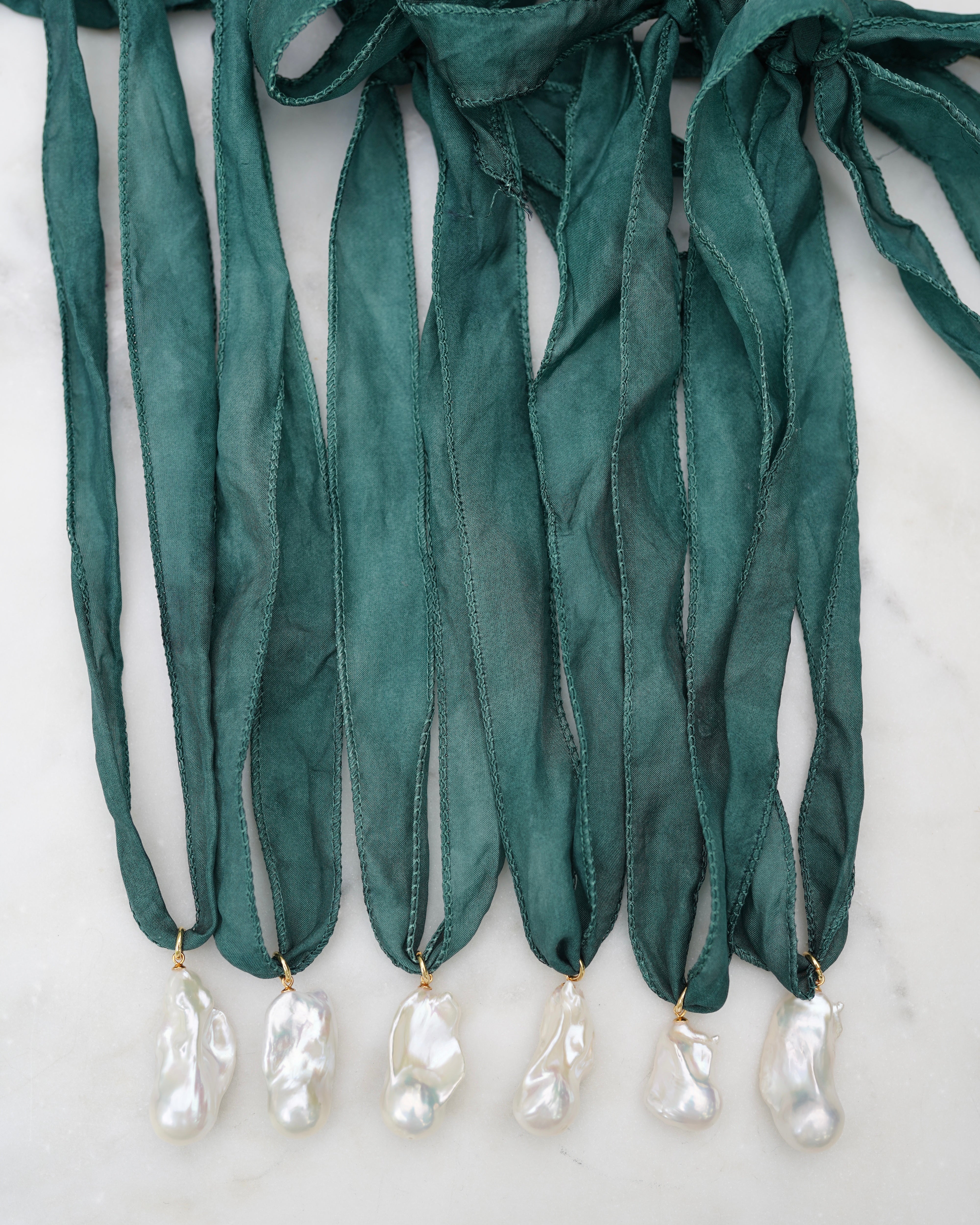Green ribbons with baroque pearl pendants on a white background